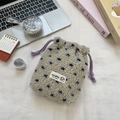 Detail of soft plush drawstring pouch with blue polka dots on a cozy desktop setting - Cream with Blue Polka Dots