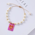 Detail of beaded heart charm bracelet with freshwater pearls and adjustable brown cord - Purple Pink Background Red Heart