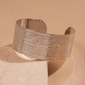 Vista macro detallada del brazalete ancho de plata con patrones de mariposas en relieve fino - Textura Plateada