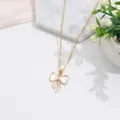 Elegante collar dorado con colgante de lazo, nácar y circonitas sobre mármol - Lazo Oro Nácar