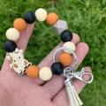 Wristlet keychain with colorful silicone beads, cow charm and white tassel on green grass - White