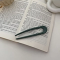 Elegante forcina per capelli a U verde scuro per acconciature su sfondo di libro aperto - Verde Smeraldo