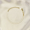 Detail van een gouden platte slangenarmband op zijden achtergrond met kreeftsluiting - Enkelbandje / Goud