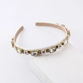 Close-up of pearl and crystal headband with gold filigree details on white stand - White