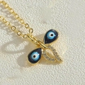 Macro shot of gold butterfly pendant with evil eye enamel wings and zircon accents - Double Eye Bowknot