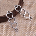 Connettori a cuore cavo in argento per gioielli fai-da-te su sfondo di legno naturale - Argento Antico