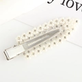 Close-up of a silver hair clip featuring white pearls and sparkling leaf-shaped rhinestones - White