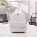 White quilted backpack with rose gold floral emblem and stylish webbed shoulder straps - White