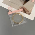 Thick transparent EVA jewelry pouch with pink zipper holding a golden bangle - 50 Silk Pink Transparent Circle Slider Bag / 11x11cm
