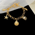Macro shot of gold stainless steel bracelet with starfish shell pendants and OT toggle clasp - Gold-Starfish