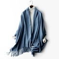 Blue knitted wool shawl with fringe tassels on hanger over a white sweater - Denim Blue