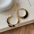Detail of C-shaped leopard resin earrings with gold metal lining on a textured book - C-Shaped Patchwork Hoop / Gold Tortoiseshell (Silver Earring Post)