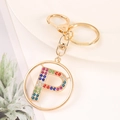 Detail of gold letter P keychain with colorful rhinestones on white plate background - Letter P