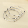 Macro detail of three silver titanium steel bangles with polished beads on fabric - Inner Diameter 60mm / 3 Rings / Steel