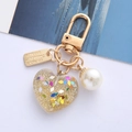 Detailed macro view of heart resin keychain with colorful glitters and a white pearl - Champagne