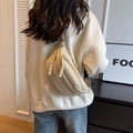 Sac de poitrine beige en toile avec lettres brodées porté sur le dos d'un modèle - Kaki