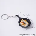 Miniature black frying pan keychain with realistic fried dumplings in a 45-degree view - Fried Dumplings Pan - Keychain