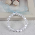 Close-up of a white imitation pearl bracelet with a light blue organza bow on wood background - 8MM Pure White Pearl With Blue Ribbon Bracelet