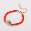 Detailed view of woven red string bracelet with rose gold interlocking rings and roman numerals - Rose Gold
