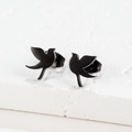 Detail of minimalist matte black stainless steel bird studs on a textured stone surface - Flying Bird / Black