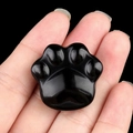Polished black obsidian cat paw stone carving held in hand for size reference - Obsidian