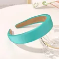 Detail of turquoise satin sponge headband with non-slip lining next to a glass bowl - Lake Green