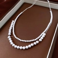 Detailed macro view of double-layered silver pearl necklace with gradient bead design - Silver