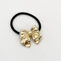 Detailed close-up of polished golden alloy bow charm on high-elastic black hair tie - Rounded Gold