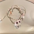 Macro detail of hand-woven owl pendant with pink eyes and colorful beads on mirror - White/Owl Shape