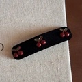 Detailed view of a black velvet hair clip with red cherry patterns on beige linen background - Red Cherry Black Velvet Rectangular BB Clip