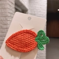 Detail of a handmade crochet carrot hair clip on a white fashion jewelry card display - Carrot