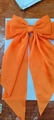 Detailed view of an oversized orange satin hair bow clip with elegant long ribbons - Bright Orange
