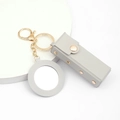 Close-up of grey PU leather lipstick holder keychain with mirror and gold hardware - Gray