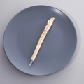 Unique spine-shaped ballpoint pen in off-white plastic finish on dark ceramic tray - Style C (Spine Shape)