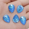 Vista macro di strass in resina a goccia blu con trama a scaglie di pesce sulla mano - Blu iridescente (5)