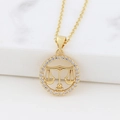 Detail view of gold Libra zodiac necklace with cubic zirconia paving on marble surface - Libra