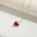 Detail of red enamel heart pendant with golden chain on white geometric background - Red