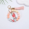 Detailed close-up of pink silicone beaded wristlet keychain with floral charm and soft tassel - Peach Pink Floral