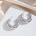 Orecchini a cerchio grossi a forma di C in argento lucido su supporto bianco minimale - Argento