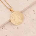 Macro detail of golden 18K zodiac pendant with relief face on textured stone background - 8#Virgo