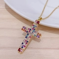 Gros plan d'un pendentif croix en or rose avec zircons colorés sur fond de bois - Style Croix Zirconia Multicolore (0100J)