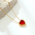 Detailed close-up of a vintage heart necklace with red zircon on a grey stone pedestal - Red Heart / Gold Red Heart
