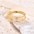 Detail of a double-layered gold ring featuring a sparkling round zircon on stone texture - US 6 / Gold