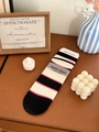 Detail von gestreiften Baumwollsocken mit Rippenstruktur auf rustikalem Holzhintergrund - Gestreift Schwarz