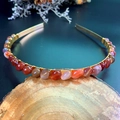 Detailed close-up of handmade gold headband with natural red crystals on wooden block - Red Agate with Gold Wire Gold Headband