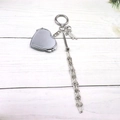Close-up of heart-shaped silver keychain with metallic mesh tassels and bow detail - Silver Round (Heart Mirror Style)