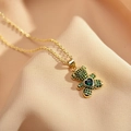 Gold teddy bear necklace with green heart-shaped crystal pendant on beige fabric - Green Zircon
