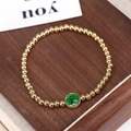 Pulsera retro de cuentas doradas con colgante religioso verde sobre fondo de madera - Verde