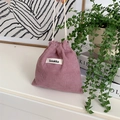 Détail du sac à cordon en velours côtelé rose montrant la texture et l'étiquette de marque - Rose Lotus