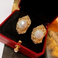 Detalle de pendiente geométrico dorado con perla blanca en un estuche de joyería - Pendientes de clip / Dorado